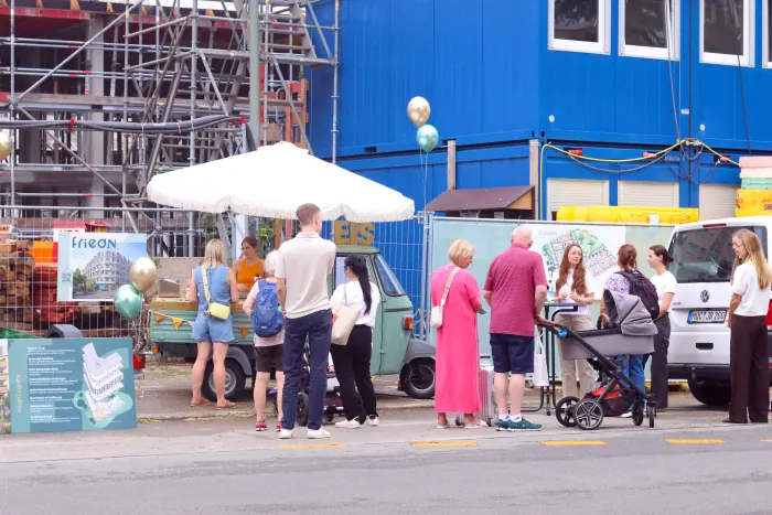 Gäste stehen beim Nachbarschaftsfest an der Eis-Ape vor der Baustelle