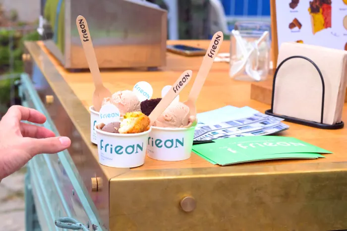 Eisbecher und Holzlöffel mit dem Logo des Veranstalters auf der Theke der Ape