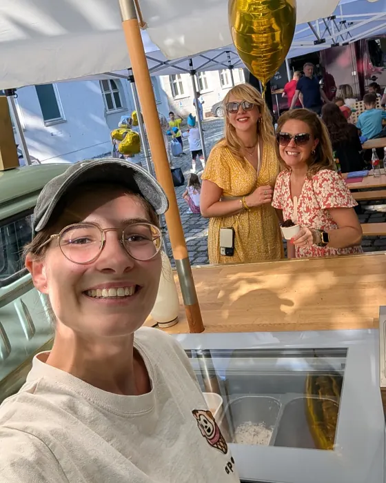 Lachendes Selfie vom apeice-Team am Stand, dahinter zwei Gäste