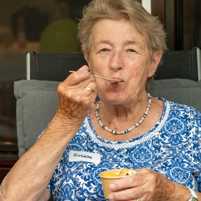 Seniorin probiert Eis aus dem Becher