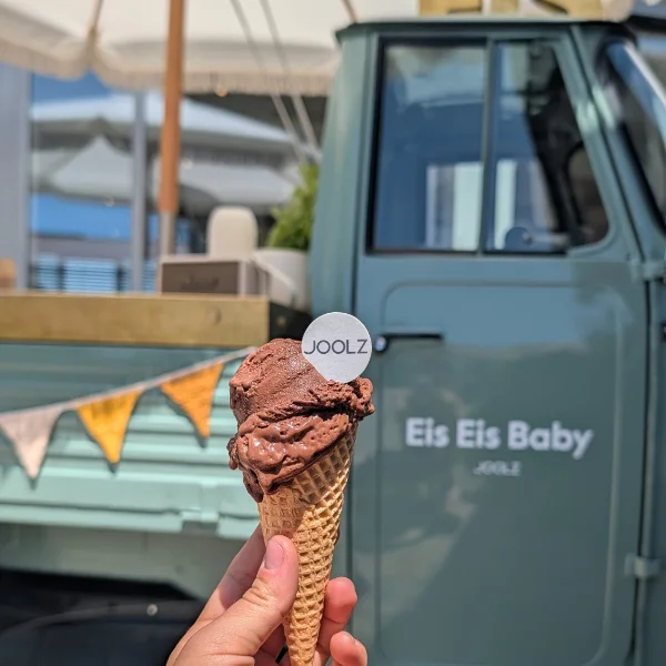 Eine Hand hält eine Waffel mit Schokoladeneis vor der Eis-Ape